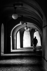 Silhouette Of A Man Walking Through A Dark Archway In Prague