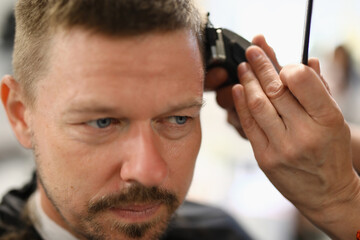 Portrait of man whose stylist cuts with hair clipper. Skills training hairdresser concept
