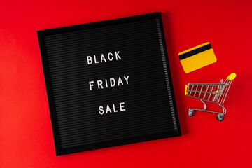 Text Black friday on black letter board, gift, shopping cart and credit card and on red background. Concept season sales time. Flat lay Top view Copy space Template layout for your design.