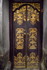 Decorated door in golden and dark wood in Bali, Indonesia