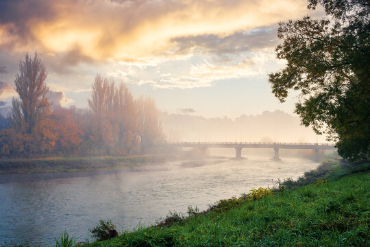 misty morning sunrise on the river. beautiful autumnal scenery with glowing sky. bridge in the distance. pravoslavna embankment of uzhgorod, ukraine
