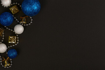 Horizontal shot of three blue balls and three decorative snowballs and beads at left on black background. Top view with copy space for text.