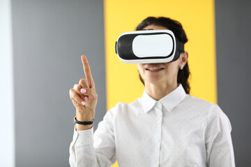 Woman in virtual reality glasses stands and holds her thumbs up. Immersion in the world of virtual...
