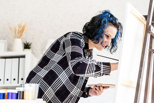 Creative Woman With Blue Dyed Hair Painting In Her Studio