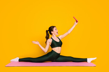 Photo of sporty lady sit mat floor stretch legs share results make selfies wear sports suit isolated yellow color background