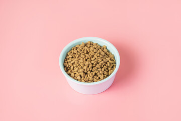 Cat dry food in a bowl on a pink background. The concept of a diet for pets, the choice of food for...