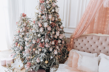 Beautiful room with new year decor with christmas tree and pink gifts near the bed and window - 391482714