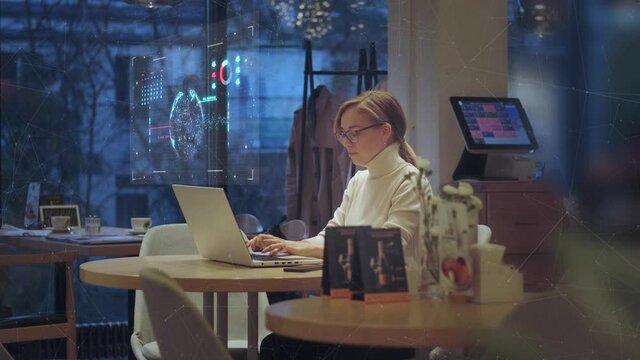 Additional reality and holographic interface. Young business woman works remotely in a cafe with a laptop, views information on a holographic screen