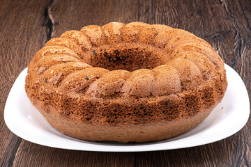 Round cupcake with chocolate chips on a white plate over a wooden background. Copy space.