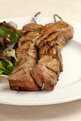 brochettes de boeuf grillées et salade dans une assiette