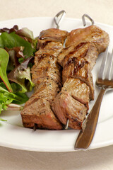 brochettes de boeuf grillées et salade dans une assiette