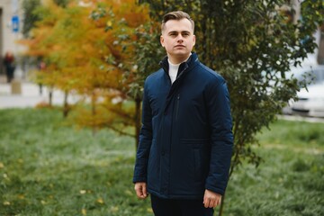 Portrait of a stylish man with a beard dressed in a coat, outdoors