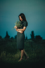 girl with a bouquet of wildflowers in a field in the evening