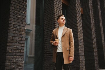 Portrait of a stylish man with a beard dressed in a coat, outdoors