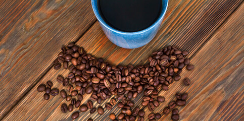 Cup of black coffee with roasted coffee beans on a wooden backgound. Top view.