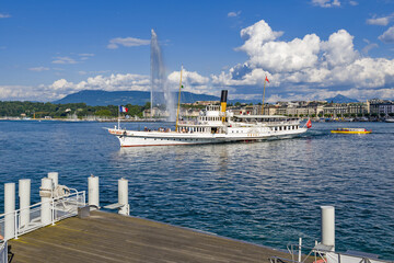vintage steamboat arriving at a pier on Lake Geneva with the water jet in background in Geneva Switzerland - obrazy, fototapety, plakaty