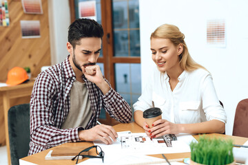 A man sits with a girl at a table and discuss work