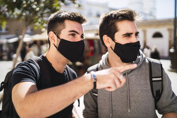 Closeup focus shot of young men wearing facemask on a sunny day
