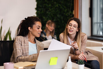 Group of a young female businesswoman working in an office while sitting at a table with colleagues.