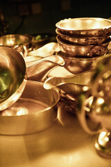 Heavy silver bowls and sauce bowls stacked in golden light.