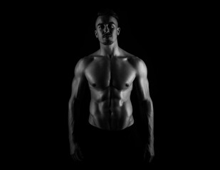 Obraz na płótnie Canvas Muscular male torso of fit bodybuilder on black background in black and white