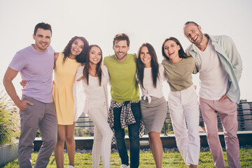Photo of young smiling cheerful positive good mood happy group of people hug each other having fun outside on rooftop