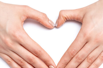 Fototapeta premium Closeup of hands of young woman forming shape of heart with her manicured fingers on white background