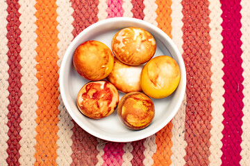Top view Easter eggs, colored traditionally with onion peels, in a bowl on an ethnic carpet or table cloth
