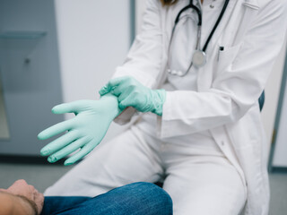 Junge Ärztin zieht sich vor der Behandlung Handschuhe an