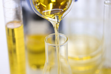 Golden liquid is poured from flask into test tube. Petroleum research and experiences concept