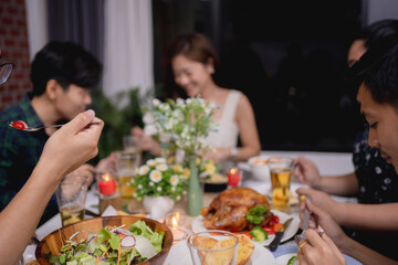 Close up of a young man's hand eating food, Group of Asian people at a party eating in a restaurant.