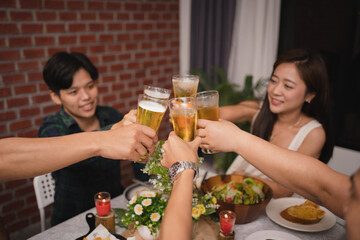 Group of Asian friends had a party at home in the evening. They are eating and drinking beer.