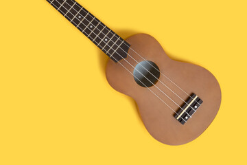 Flat lay of ukulele on a bright yellow background. Musical equipment.