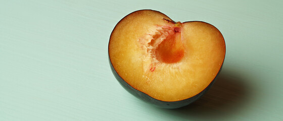 plum on a green table, cut in half with stone