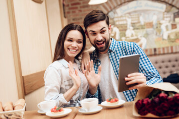 Young Couple Using Tablet in Modern Cafeteria.