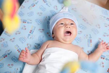 Baby with hat crying in bed