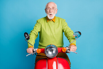 Photo of retired grandpa ride motorcycle open mouth wear spectacles green pullover isolated blue...
