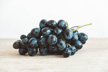 One bunch of freshly picked black grapes on a old wooden table. Copy, empty space for text