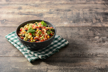 Mexican salad with quinoa in bowl on wooden table. Copy space