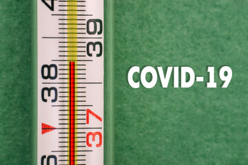 Close up of high temperature thermometer with COVID-19 text. Signs of coronavirus disease. Viral symptoms. Body temperature checks