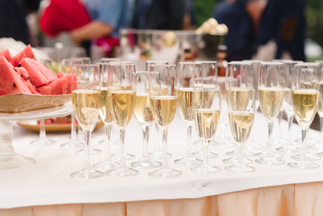 Glasses of champagne with visible bubbles and reflected guests on a table with a blurred background. Holiday concept