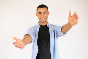 Young smiling man against a white background isolated feels confident giving a hug to the camera.