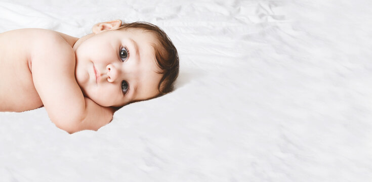 Funny Little Kid Wearing. Portrait Of A Cute Baby 6 Months Old Lying On A White Blanket. Beautiful Toddler. Looking At The Camera