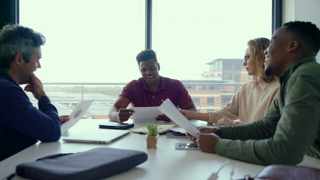 Diverse team of students preparing for important intern exam sitting around table testing each-other in conference room