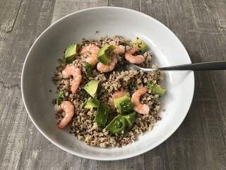 Red and white quinoa with fresh prawns and avocado against a wooden background