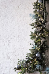 Christmas decoration of branches and garlands on the background of an old brick wall