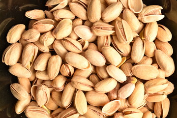 Organic salted pistachios, close-up, on a black background.