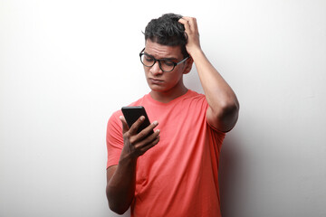 Young man of Indian origin looking at his mobile phone with a troubled face