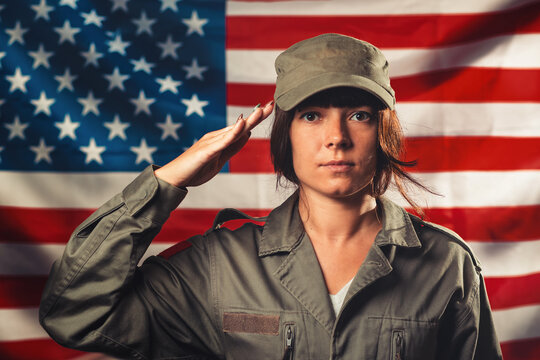 Veterans Day, Memorial Day, Independence Day. Portrat of female soldier saluting against the background of the American flag. Concept of national American holidays and patriotism