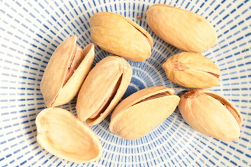 Organic salted delicious pistachios in a ceramic plate, close-up